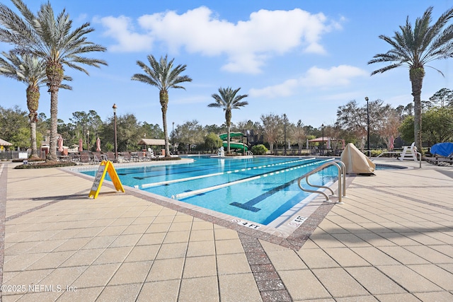 pool featuring a water slide and a patio area