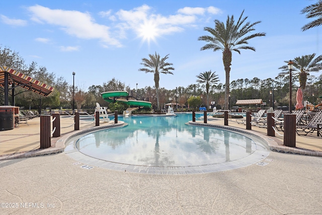 pool featuring a water slide and a patio