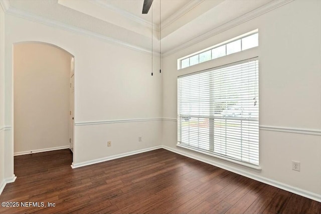 spare room with dark wood-type flooring, ceiling fan, a raised ceiling, and crown molding