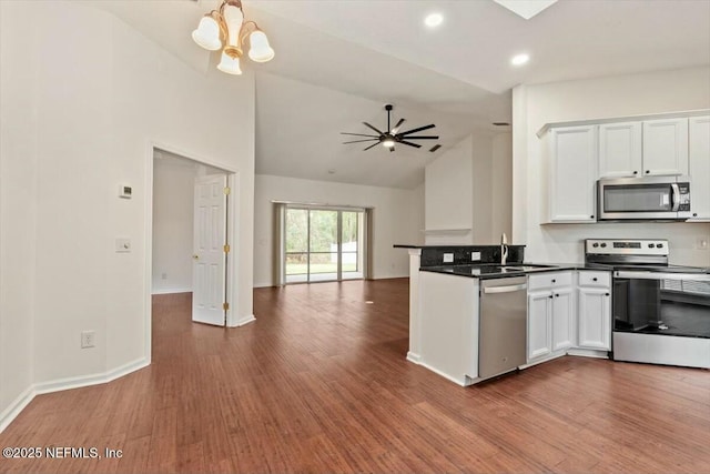 kitchen with kitchen peninsula, hardwood / wood-style floors, ceiling fan with notable chandelier, stainless steel appliances, and white cabinets