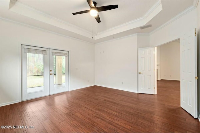 spare room with a raised ceiling, french doors, and dark hardwood / wood-style floors