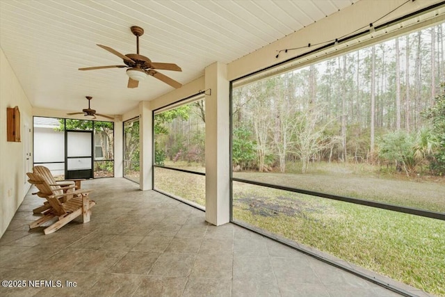 unfurnished sunroom featuring ceiling fan and a wealth of natural light