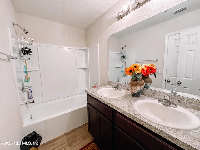 bathroom featuring bathing tub / shower combination, a textured ceiling, hardwood / wood-style flooring, and vanity