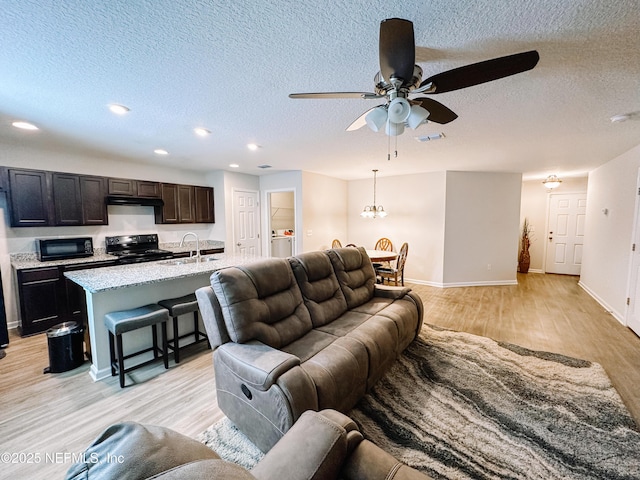 living room featuring sink, a textured ceiling, ceiling fan, and light wood-type flooring