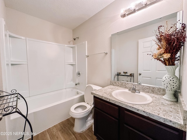 full bathroom with hardwood / wood-style floors, vanity, shower / bathtub combination, a textured ceiling, and toilet