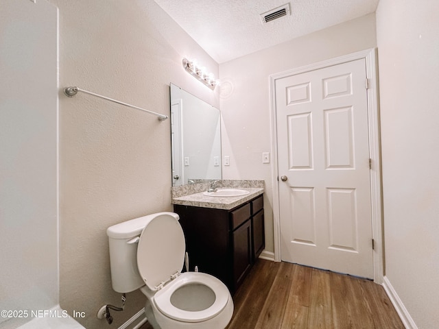 bathroom featuring toilet, a textured ceiling, hardwood / wood-style floors, and vanity