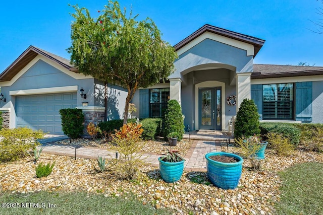 view of front of property with an attached garage, stone siding, french doors, and stucco siding