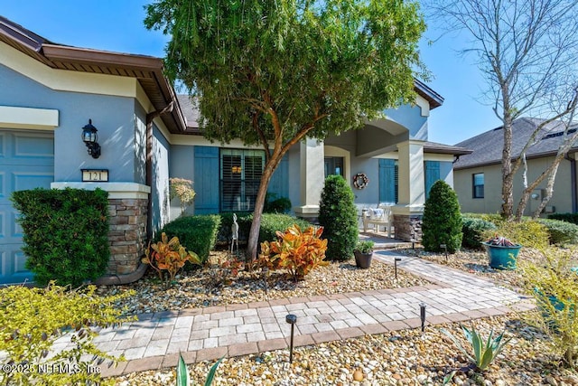 property entrance with covered porch, an attached garage, and stucco siding