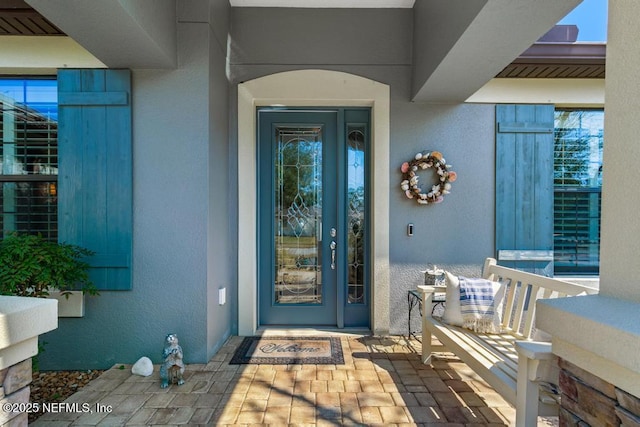 entrance to property featuring covered porch and stucco siding