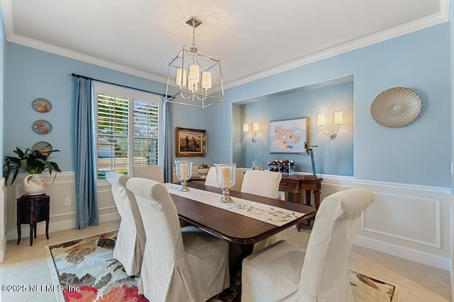 dining area with a notable chandelier, light tile patterned floors, wainscoting, and crown molding