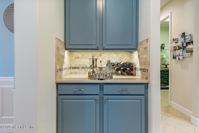 bar featuring light tile patterned flooring, backsplash, and baseboards