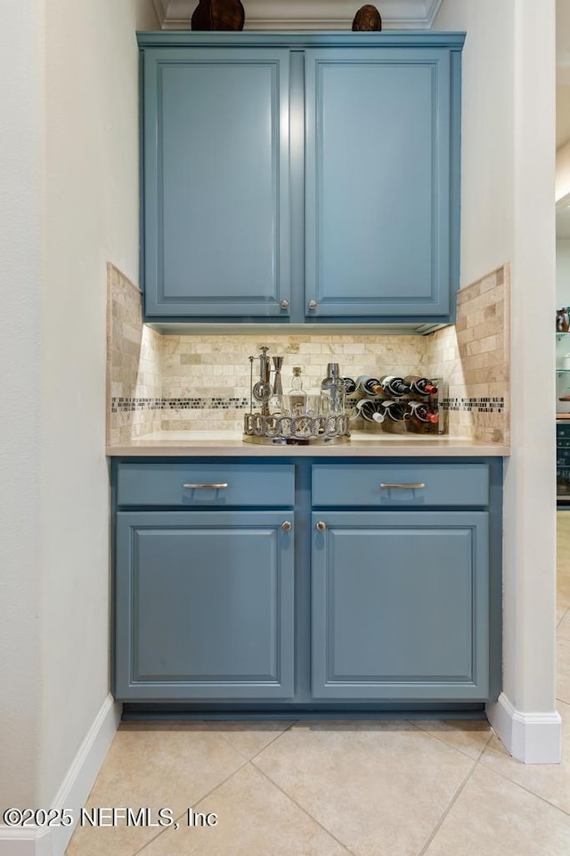 bar featuring light tile patterned flooring, backsplash, and baseboards