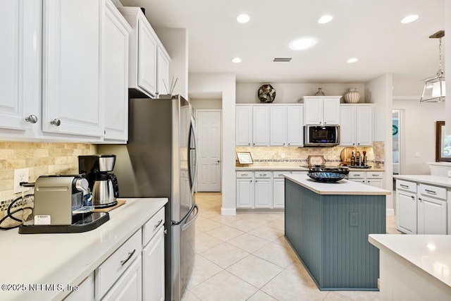 kitchen featuring light tile patterned floors, visible vents, stainless steel microwave, light countertops, and white cabinetry