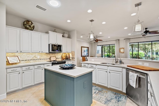 kitchen featuring visible vents, appliances with stainless steel finishes, light tile patterned flooring, a sink, and a kitchen island