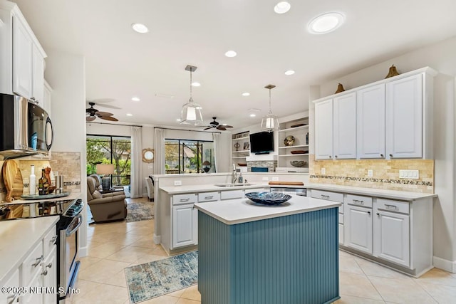 kitchen featuring light tile patterned floors, open floor plan, light countertops, stainless steel appliances, and a sink