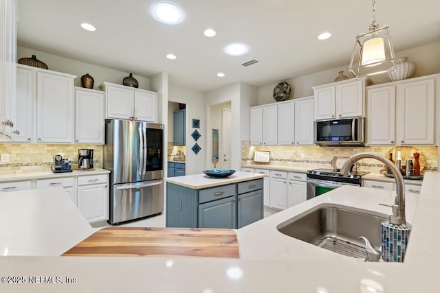 kitchen with appliances with stainless steel finishes, white cabinets, a sink, and light countertops