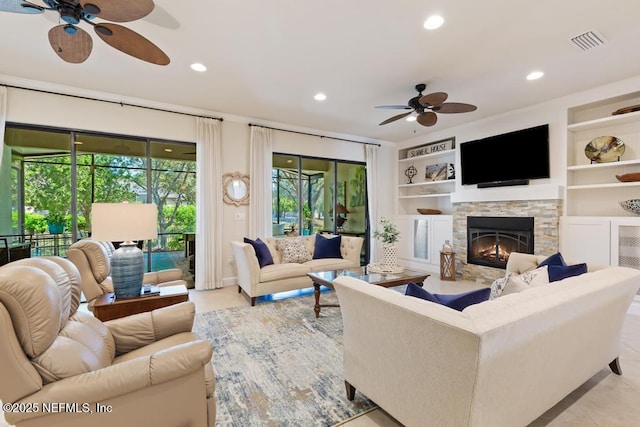 living area featuring built in features, recessed lighting, visible vents, a ceiling fan, and a stone fireplace