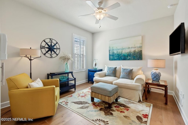 living area with baseboards, a ceiling fan, and wood finished floors