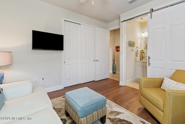 living room with a barn door, wood finished floors, and baseboards