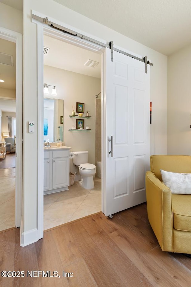 bathroom with toilet, wood finished floors, visible vents, vanity, and walk in shower