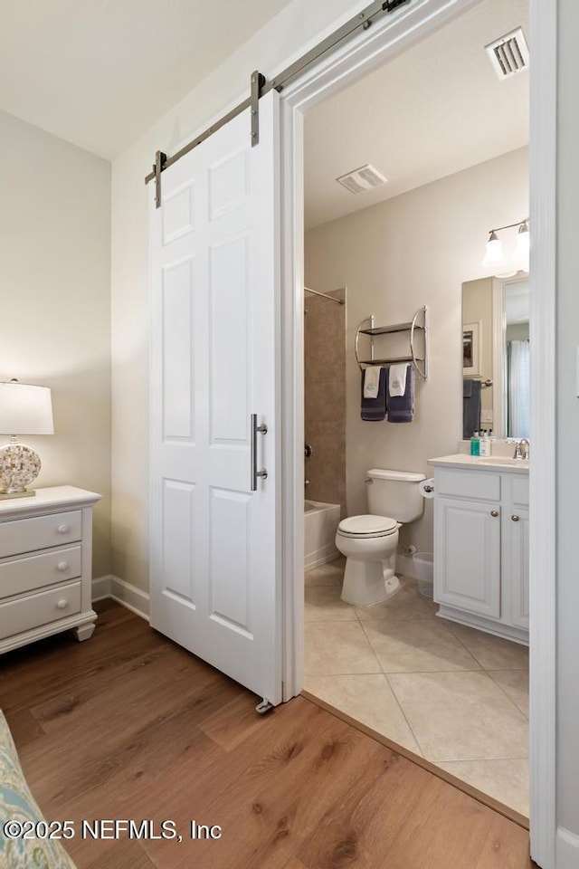 bathroom with toilet, visible vents, wood finished floors, and vanity