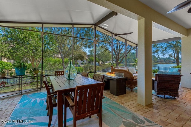 sunroom / solarium with a water view, lofted ceiling with beams, and a ceiling fan