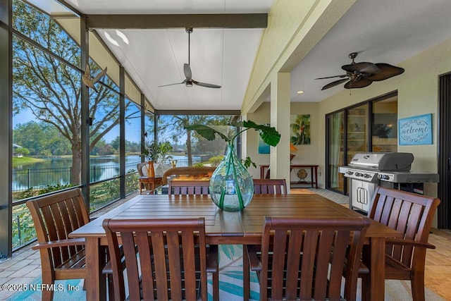 sunroom / solarium featuring beamed ceiling, a water view, and a ceiling fan