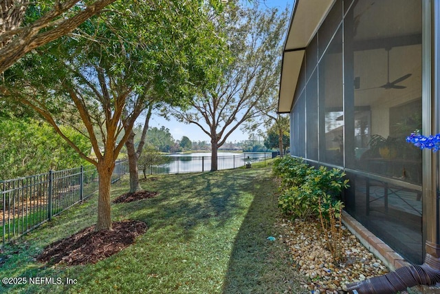 view of yard with a water view, a fenced backyard, and a sunroom