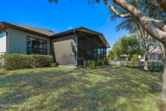 rear view of property with a sunroom, a lawn, and stucco siding