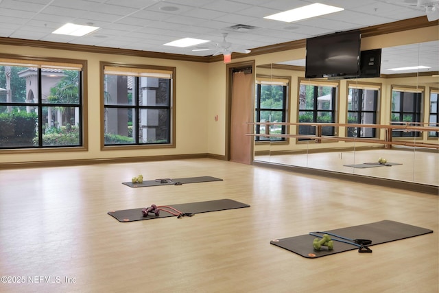 exercise room featuring crown molding, a paneled ceiling, visible vents, wood finished floors, and baseboards