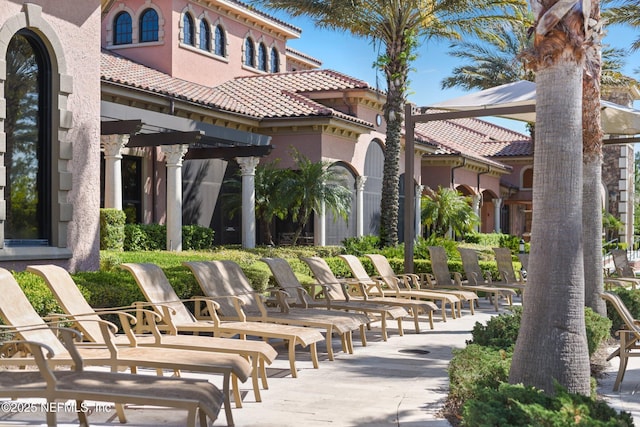 rear view of property with a tile roof, a patio, and stucco siding