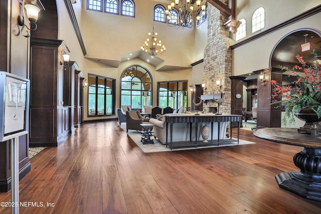 living area featuring a notable chandelier, a stone fireplace, and hardwood / wood-style flooring