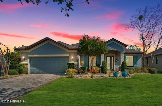 ranch-style house featuring a front lawn, decorative driveway, a garage, and stucco siding