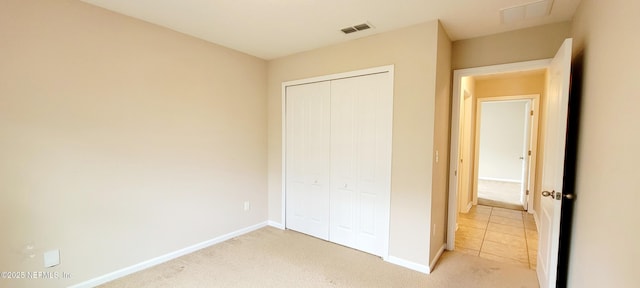 unfurnished bedroom with baseboards, visible vents, a closet, and light carpet