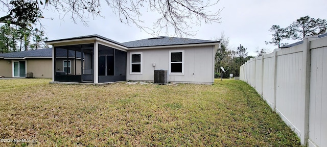 rear view of property with a yard, central air condition unit, fence, and a sunroom