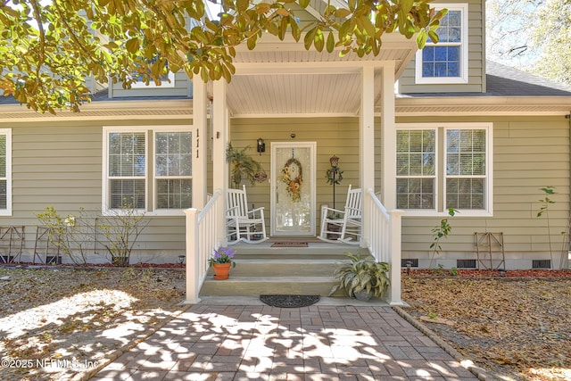 property entrance featuring crawl space, a porch, and a shingled roof