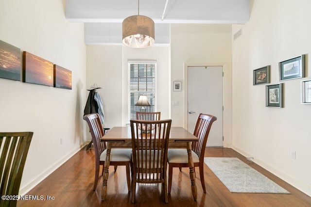 dining area featuring beamed ceiling and dark hardwood / wood-style floors