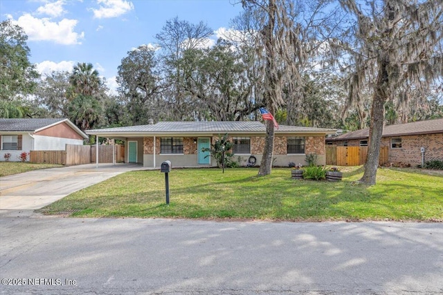 ranch-style home featuring a carport, a front yard, concrete driveway, and fence