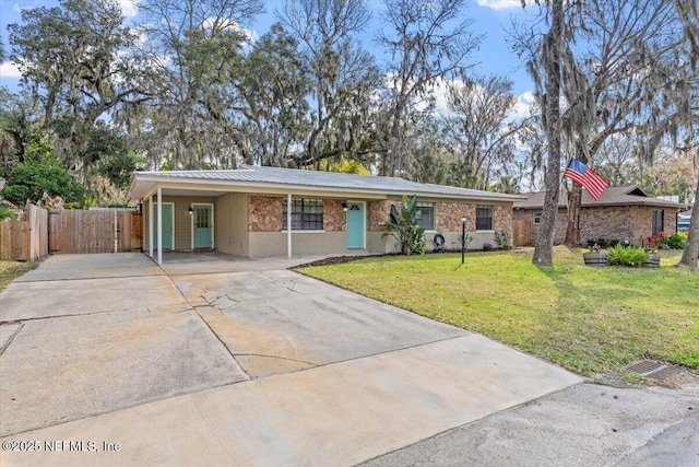 ranch-style house with an attached carport, fence, a front lawn, and concrete driveway