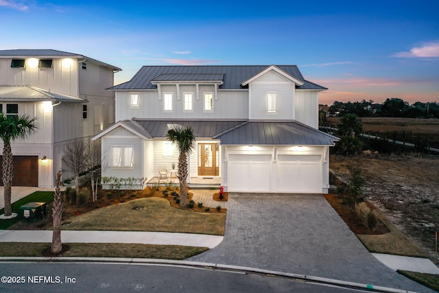 modern farmhouse style home featuring a garage, metal roof, decorative driveway, and a standing seam roof