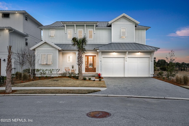 view of front of property with a garage, driveway, metal roof, and a standing seam roof