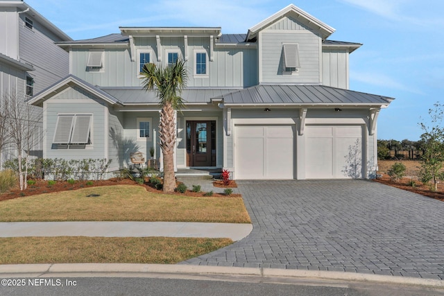 view of front of house with decorative driveway, board and batten siding, a standing seam roof, a garage, and a front lawn