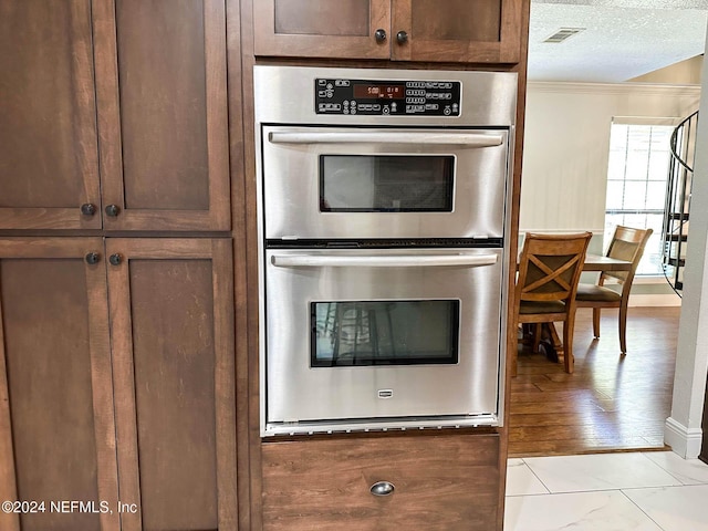 kitchen featuring double oven, a textured ceiling, and ornamental molding