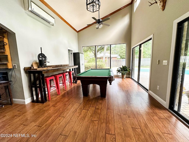 playroom with hardwood / wood-style flooring, ornamental molding, a wall mounted AC, and a towering ceiling