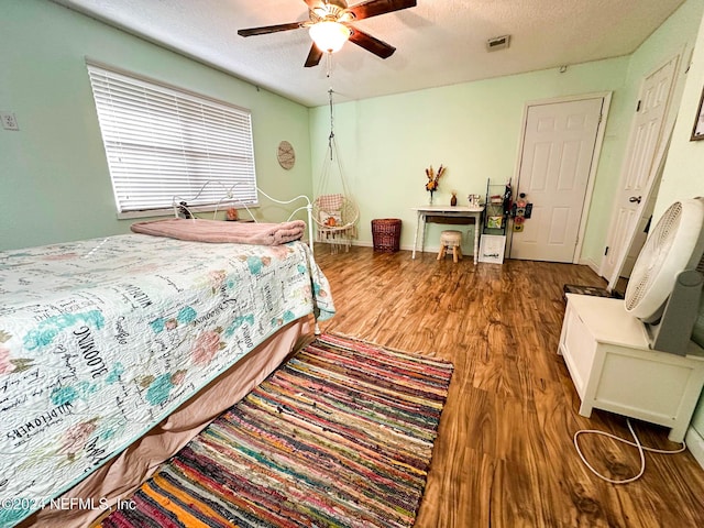 bedroom with ceiling fan, wood-type flooring, and a textured ceiling