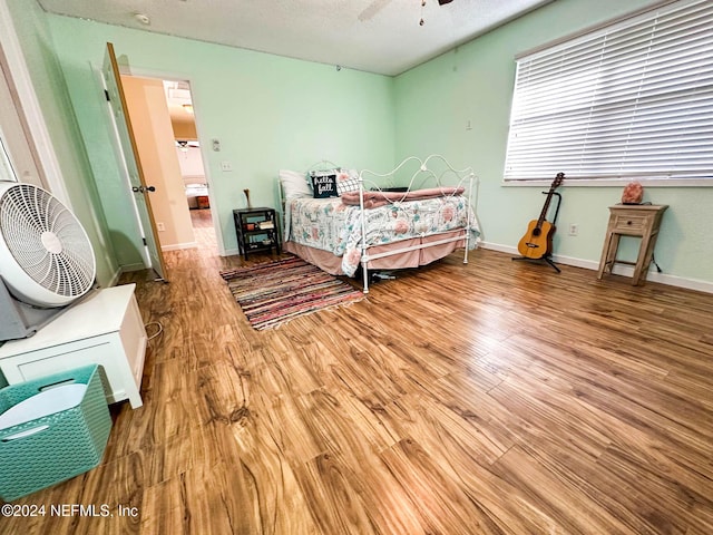 bedroom with hardwood / wood-style flooring, ceiling fan, and a textured ceiling