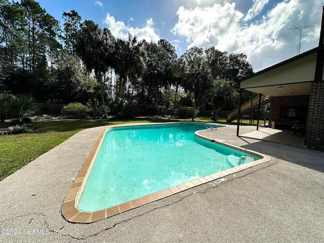 view of pool featuring a patio and a yard