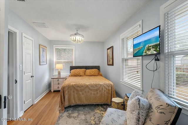 bedroom with an inviting chandelier and hardwood / wood-style floors