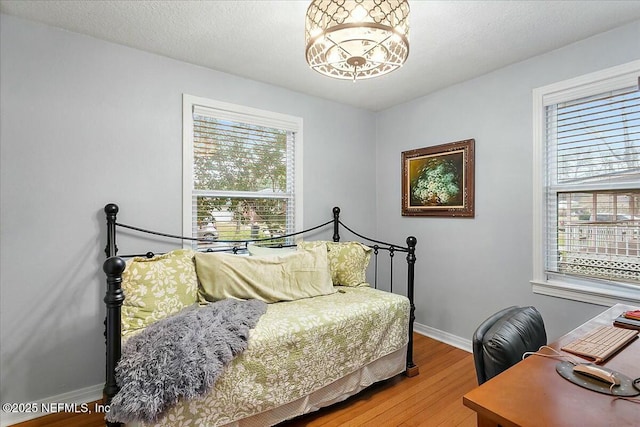 bedroom with a chandelier, a textured ceiling, and hardwood / wood-style flooring