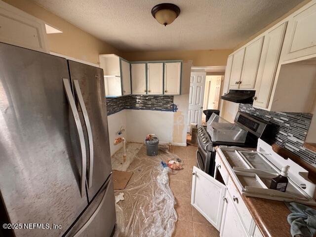 kitchen with a textured ceiling, backsplash, appliances with stainless steel finishes, and light tile patterned floors